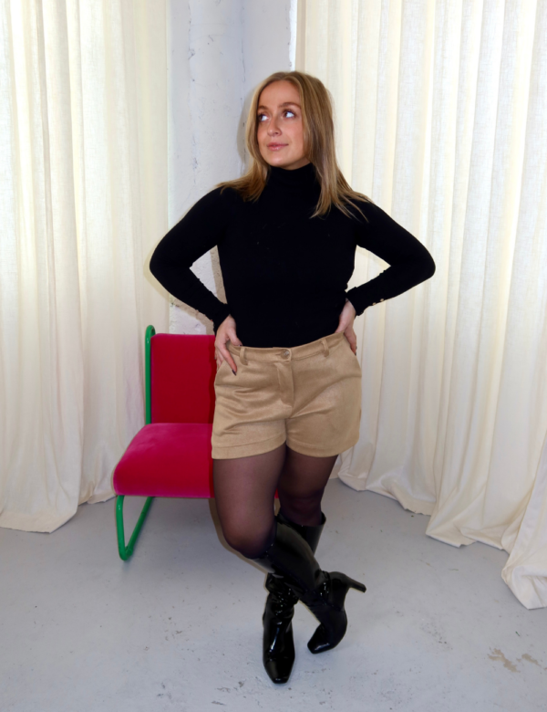 short beige en suédine avec bouton et passants pour ceinture porté avec col roulé noir et bottes