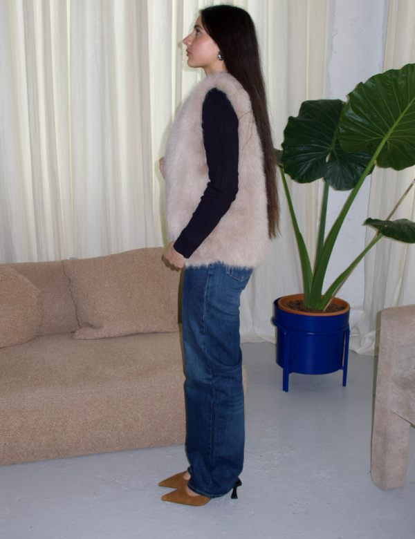 vue de côté fourrure beige sans manches avec jean bleu